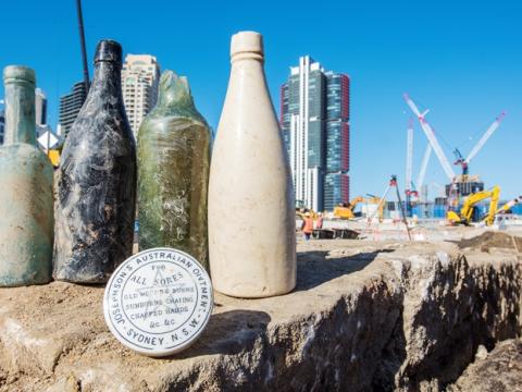 5 old glass bottles and an old jar that reads 'Josephson's Australian Ointment' are on display at the excavation area at the future site of Barangaroo Metro Station.