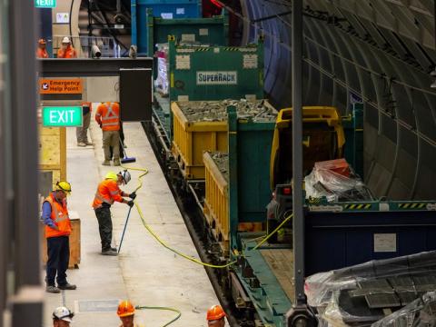 An arial view showing four construction workers on the platform as a freight train is delivering materials to the platform at East Coast Rail Link's Macquarie Park Station.