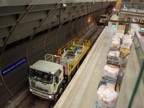 An arial view showing two trucks on the tracks delivering materials to the platform at East Coast Rail Link's Macquarie University Station.