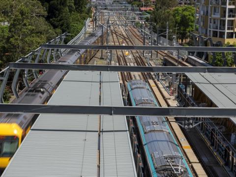 An arial shot looking down on the station platform as a Sydney Metro Train arrives at the platform next to a Sydney Trains train at Chatswood Station. 