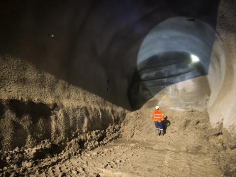 An on the ground view from inside the cavern as a construction worker inspecting the tunnel with their head torch shining a light to the top of the tunnel as tunnelling commences at Sydney Metro's Pitt Street North Castlereagh Cavern site.