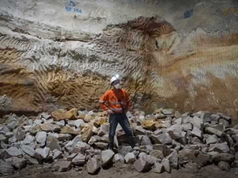 An on the ground view showing  a construction worker standing in front of a pile of sandstone that has been taken down as construction continues at Sydney Metro's Martin Place Station.