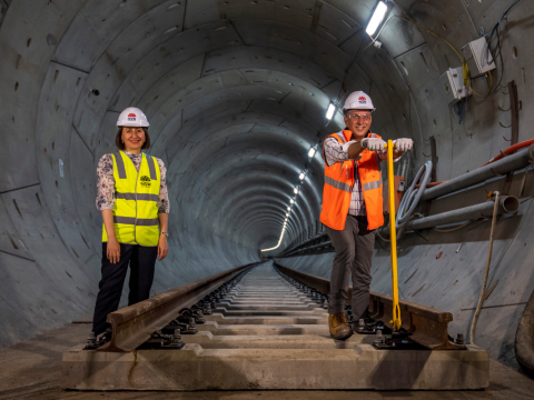 The NSW Premier and Minister for Transport standing on newly laid rail track in the tunnel at Chatswood. 
