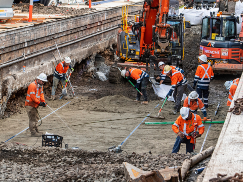 Construction workers in high viz working on reinforcing the railway track which is above the future central walk