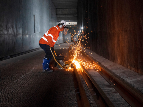 A worker in protective clothing is welding the track at Marrickville Dive site. Sparks can be seen from the welding.