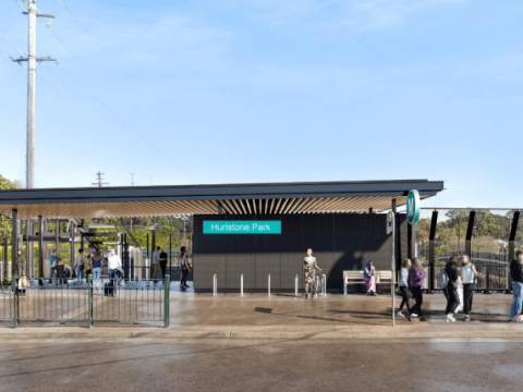 An artists impression of the entry to Hurlstone Park Station. There are people walking around and blue sky in the background.