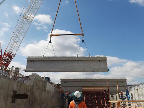 Large concrete beams are being installed by a crane in the station box of the Bella Vista Station construction site.