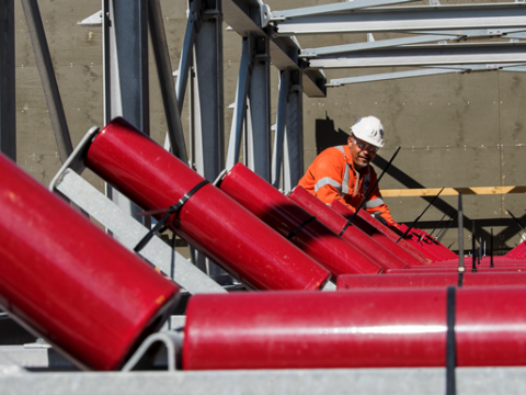 A close up shot as three construction workers are installing metal panels of the conveyer belt at Sydney Metro's Chatswood Drive. 