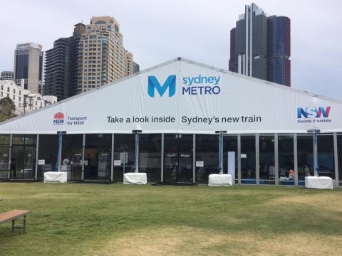 A large Sydney Metro branded marquee displaying the words 'take a look inside Sydney's new train' which was displayed at Barangaroo Reserve.