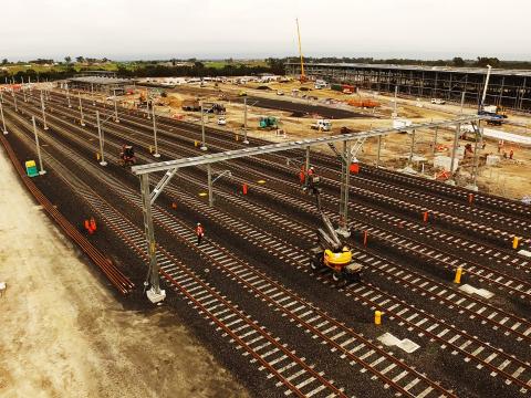 An arial view looking down at the ten tracks being laid at the Sydney Metro Train Facility at Rouse Hill with construction happening in the background.