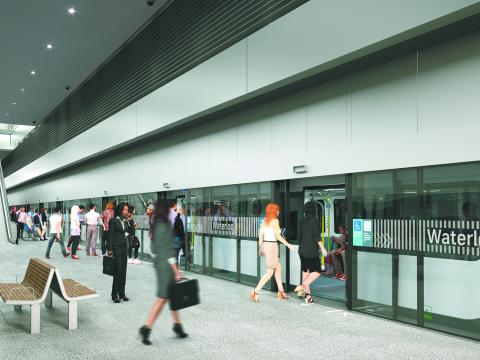 An artist's impression of commuters walking outside of Sydney Metro's Waterloo Station. Pink cherry blossom trees line the station entrance.