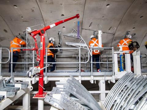 Workers aboard a M&E consist install the infrastructure for the mechanical and electrical systems inside Sydney Metro's down tunnel.