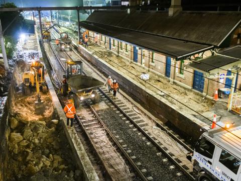A bird's eye view of construction workers in orange high-vis performing night time track works at Canterbury Station.
