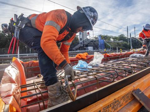 A close up view of a construction worker laying metal rods in place on site at Dulwich Hill Station.