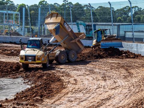 A dump truck unloads dirt at the construction site of the new Sydney International Speedway.