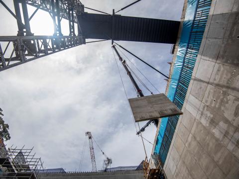 A ground up view of a crane lifting a concrete panel down to B3 level at Sydney Metro's Waterloo Station. 
