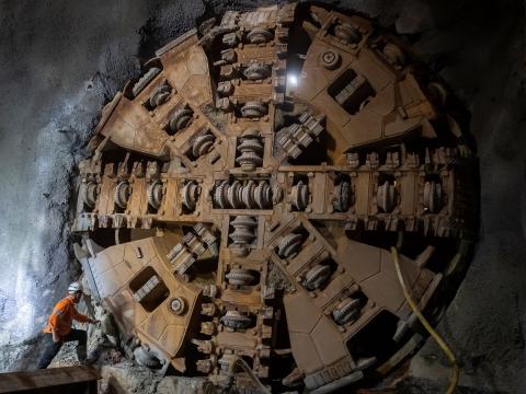 Construction worker inspecting Tunnel Boring Machine (TBM) Kathleen breaking through at Sydney Metro's Blues Point tunnel access site. 