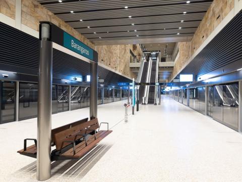 Inside of Barangaroo Station metro platform with escalators and bench for passengers opposite to the metro screen doors