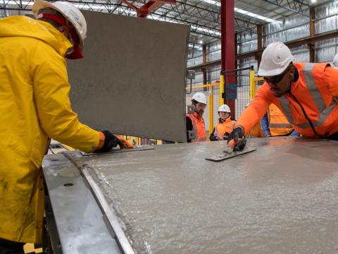 2 workers are pouring cement to produce a precast segment