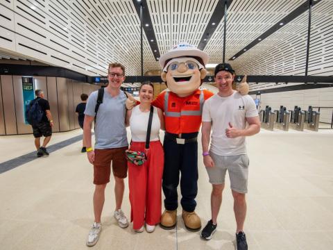 Mascot with three people posing for a photo