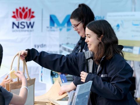 A Sydney Metro employee is handing out a bag to a stakeholder in an event