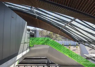 A side angle view of the top of the escalators at Tallawong Metro Station. The escalators have green glass on both sides.