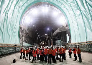 A group of people in full personal protective equipment conducting a site visit inside Sydney Metro's Martin Place Station tunnel.