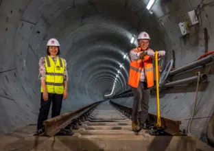 The NSW Premier and Minister for Transport standing on newly laid rail track in the tunnel at Chatswood.