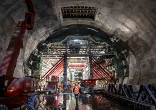 An on the ground view of a construction worker walking through the construction site as formwork is being done at Sydney Metro's Victoria Cross Cavern. 