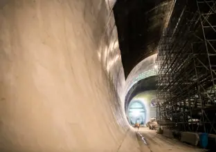 A view down the tunnel of Victoria Cross Station with a construction work in the distance and metal scaffolding on the right hand side.