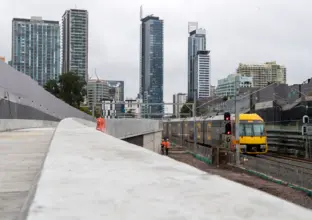 A Sydney train passing by the Chatswood Dive site. There are high rise buildings in the background.