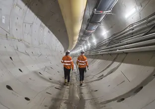 An on the ground view of two construction workers walking through Chatswood Drive Tunnels