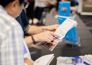 A close up shot showing community members pointing and reading information booklets at a Sydney Metro Community Information Session. 