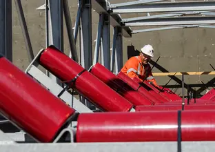 A close up shot as three construction workers are installing metal panels of the conveyer belt at Sydney Metro's Chatswood Drive.