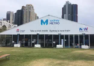A large Sydney Metro branded marquee displaying the words 'take a look inside Sydney's new train' which was displayed at Barangaroo Reserve.