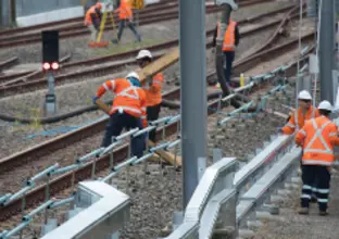 Seven construction workers working on the tracks.