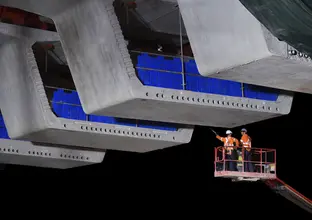 Two construction workers on a crane inspecting the bridge deck on the Windsor Road railway bridge at Sydney Metro's Rouse Hill Station.