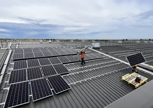 An arial view of two construction workers lifting solar panels into place at a Sydney Metro site. 