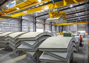 An on the ground shot showing rows on precast concrete segments lined up for production with a machine liftin one of the segments into place at Marrickville precast facility.