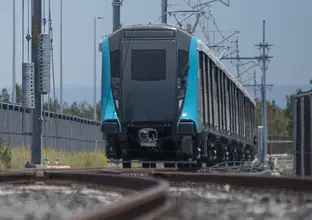 An on the ground shot looking at a Sydney Metro train coming towards the camera being tested along the tracks.