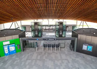 An Artist's impression of the station concourse entrance for Sydney Metro's Northwest Station prototype, showing the entrance barriers, signage to the platforms and lifts to go down onto the platform. 