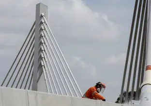An on the ground view looking up at a construction worker doing some final works on the Windsor Road railway bridge at Sydney Metro's Rouse Hill Station. 