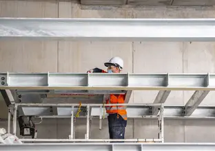 A construction worker is standing between steel beams while installing them at Waterloo Station.