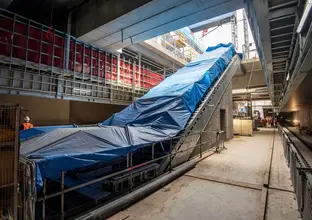 Side angle view of the new escalators covered in blue tarp that are ready for installation on B3 level (concourse) down to the platform level at Waterloo station