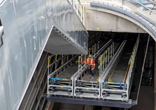 A construction worker attaches ones section of escalators to another at Central Station.