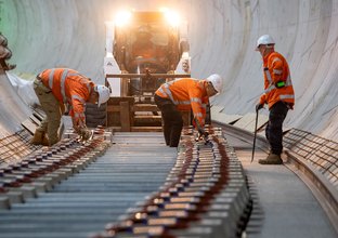 Construction workers installing noise attenuating sleepers in underground tunnel