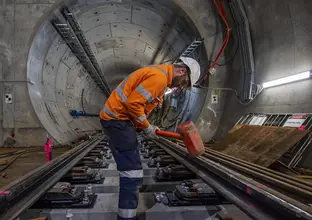 A worker is working with a big hammer to lay tracks for the Sydney Metro City & Southwest project