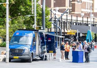 Blue Sydney Metro van on the road with a table set in front to attend visitors 