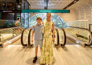 Mother and son standing at the top of the escalators under the station sign