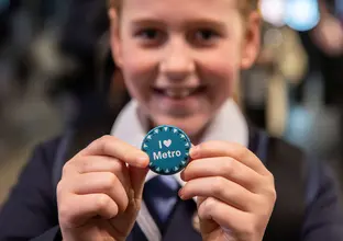 A child holding a "I love Metro" badge